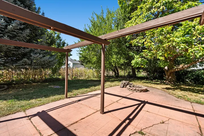 Patio with a pergola structure, concrete paver flooring, and a stone-lined fire pit