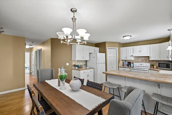 Open-concept kitchen and dining area featuring white cabinetry, tile countertops, and a ceiling-mounted chandelier