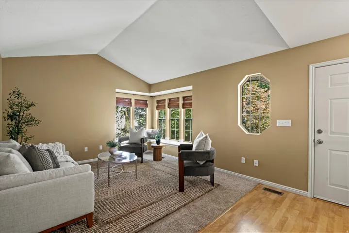 Vaulted ceiling with an octagonal window, bay window seating, and mixed flooring with wood-finish and carpet