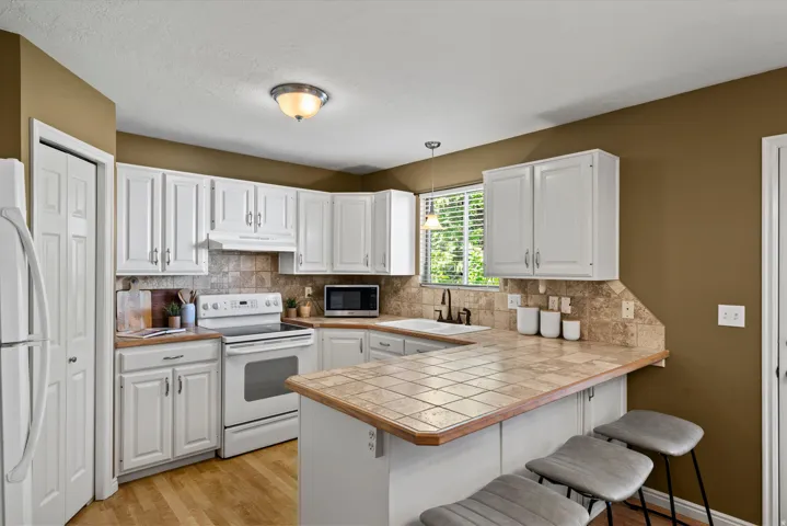 White cabinetry, a tiled backsplash, and wood-finish flooring