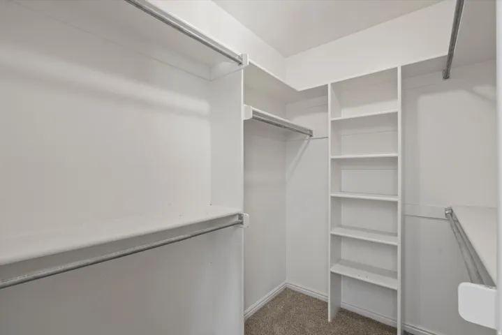 Built-in closet system featuring multiple shelves, hanging rods, and carpet flooring
