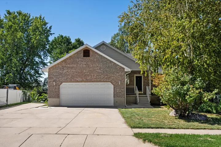 Brick exterior with siding accents, attached two-car garage, concrete driveway, and front entry porch with railing