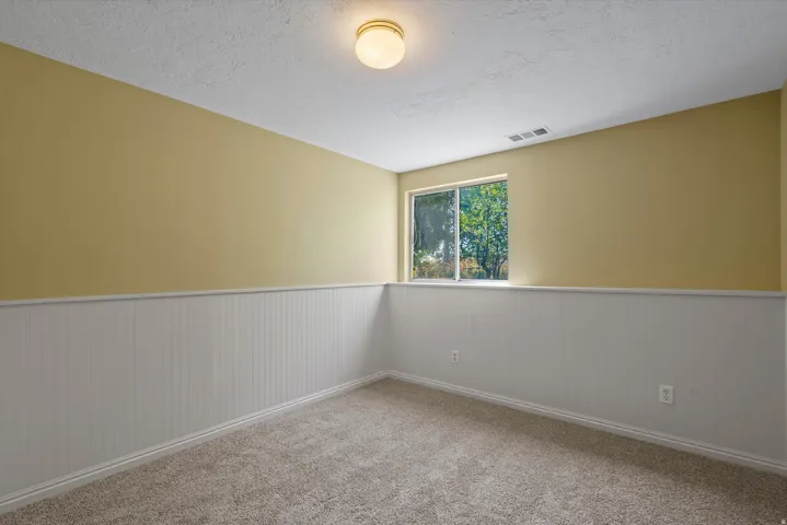 Wall-to-wall carpeting, beadboard wainscoting, and a window with exterior scenery