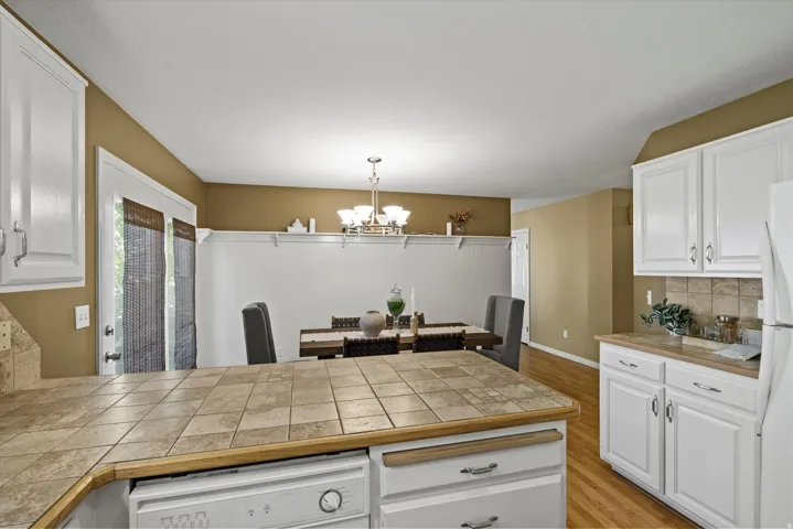 Kitchen featuring white cabinetry, tile countertops, and a built-in dishwasher