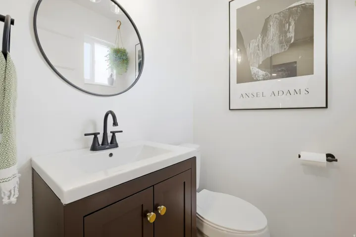 Dark wood-finish vanity with gold-tone hardware, white integrated sink, and matte black faucet