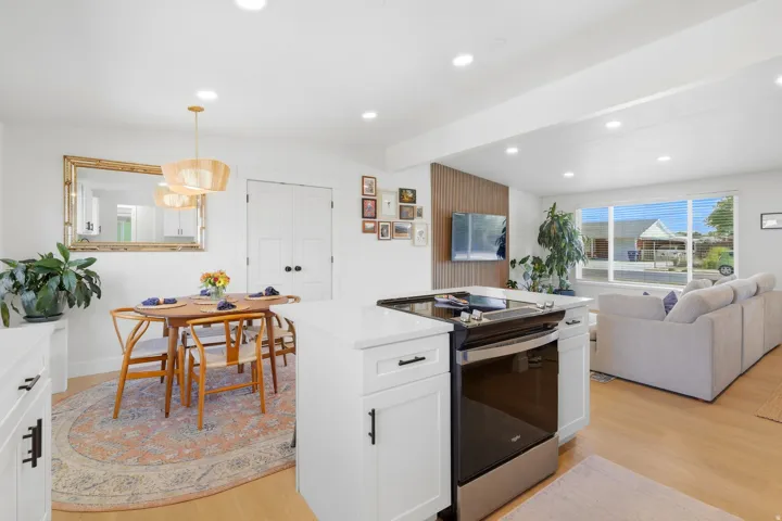 White cabinetry with black hardware, stainless steel range, light wood-finish flooring, and recessed lighting
