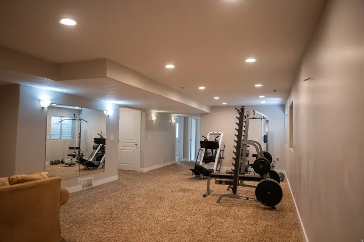 Expansive carpeted area featuring recessed lighting, wall-mounted mirrors, and sconce lighting