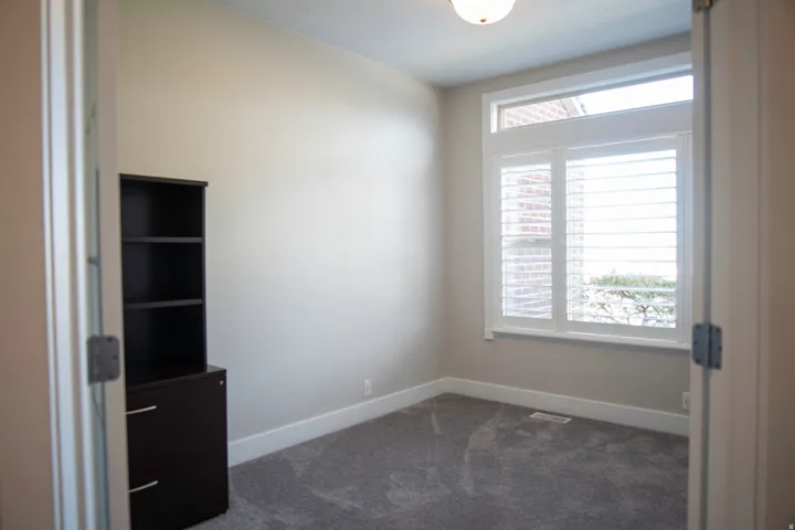 Recessed ceiling light, white window trim, white plantation shutters, transom window, and grey carpeting