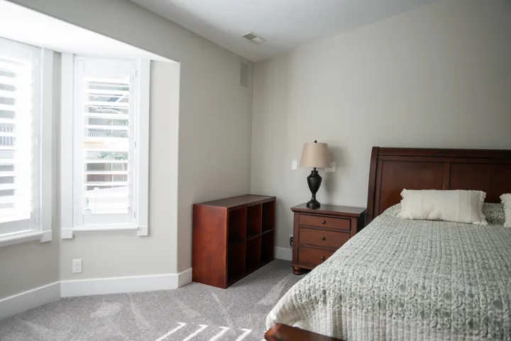 Bay window with plantation shutters, light gray wall color, and textured gray carpet