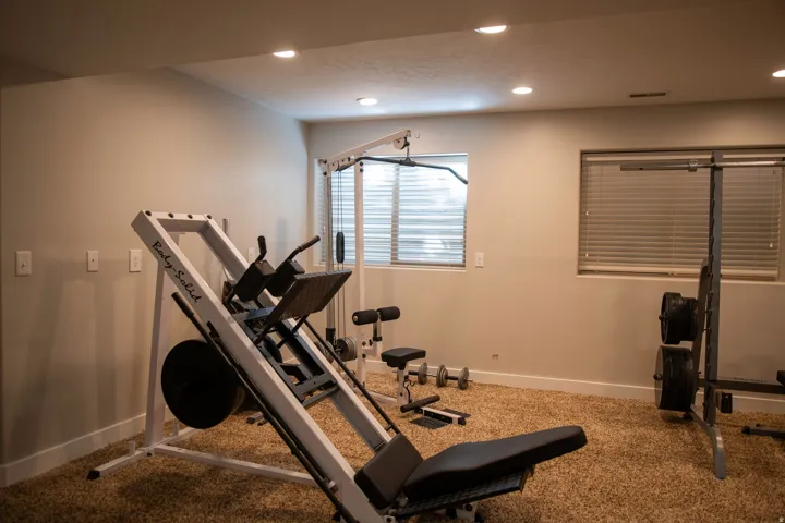 Recessed ceiling lighting, two windows with horizontal blinds, neutral wall paint, and plush carpeting