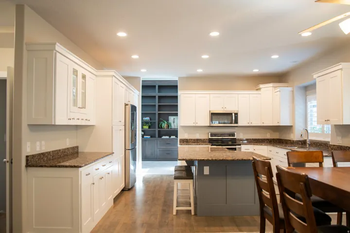 Kitchen featuring white cabinetry, dark speckled countertops, stainless steel appliances, and a central island with bar seating