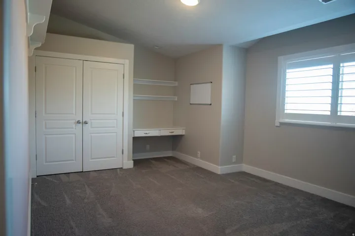 Recessed lighting, built-in shelving, integrated desk, double-door closet, and window with plantation shutters
