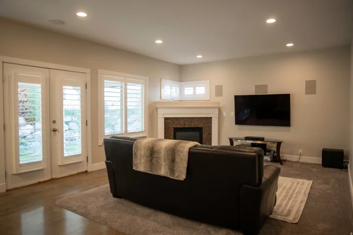 Living area featuring recessed lighting, a fireplace with a stone surround and mantel, and white plantation shutters