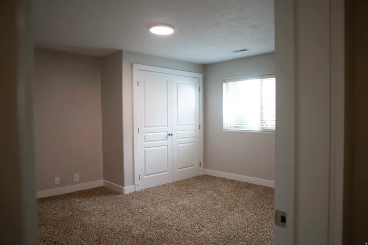 Plush carpeting, recessed ceiling lighting, a window with horizontal blinds, and a built-in closet with double panel doors