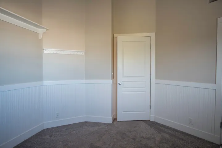 Wall-to-wall carpeting, beadboard wainscoting, and a white interior door