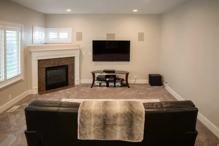 Gas fireplace with a stone-finish surround, recessed lighting, and plantation shutters