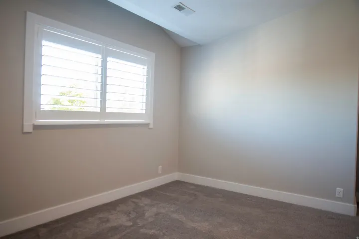 Neutral wall tones, plantation shutters, and grey carpeting
