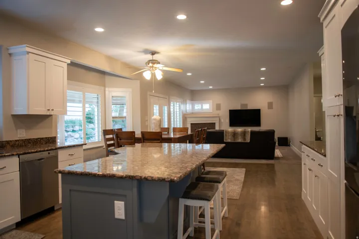 Open-concept living area with wood-finish flooring, recessed lighting, and white shaker cabinetry