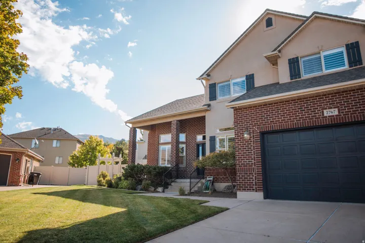 Brick and stucco exterior with a covered porch, an attached garage, and a concrete driveway