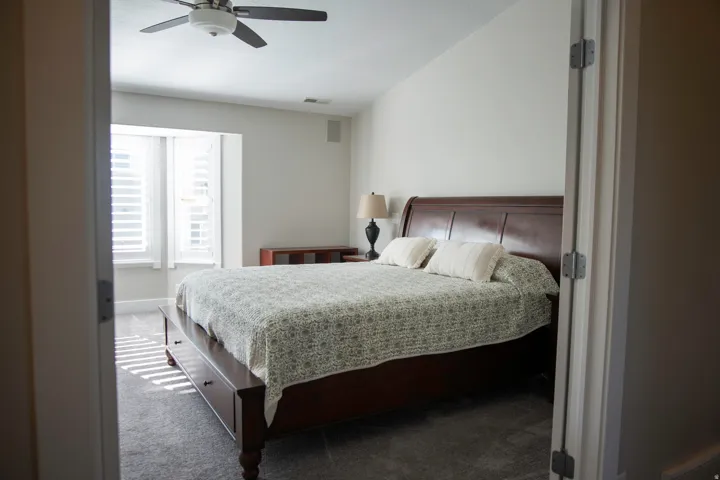 Primary Suite with carpeted flooring, plantation shutters, and a ceiling fan with integrated lighting