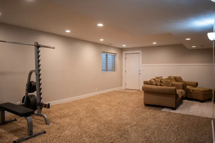 Carpeted room with recessed lighting and a single window with horizontal blinds
