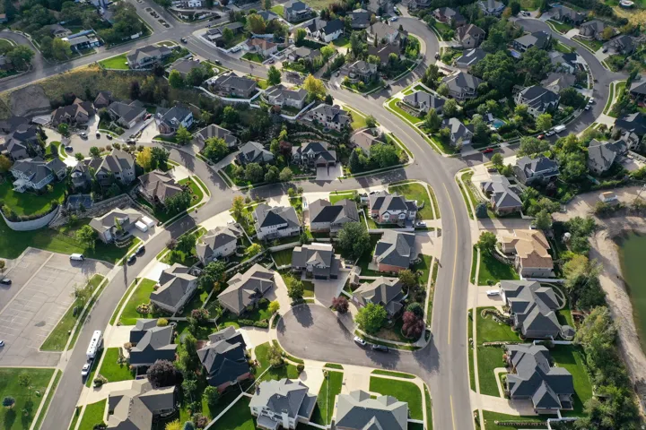 Aerial perspective of a developed residential area with paved streets, mature landscaping, and varied architectural styles
