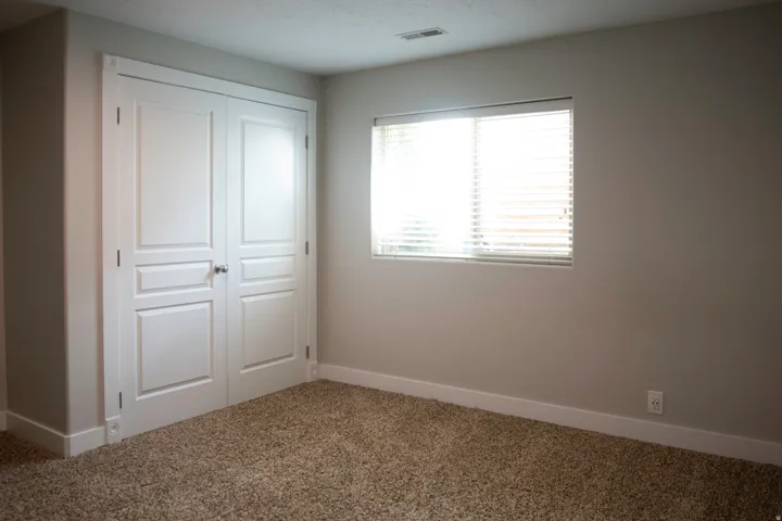 Neutral wall color, light-filtering window blinds, textured carpeting, and white trim throughout