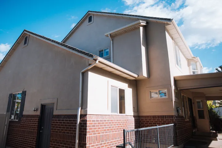 Stucco exterior featuring red brick detailing and white window frames
