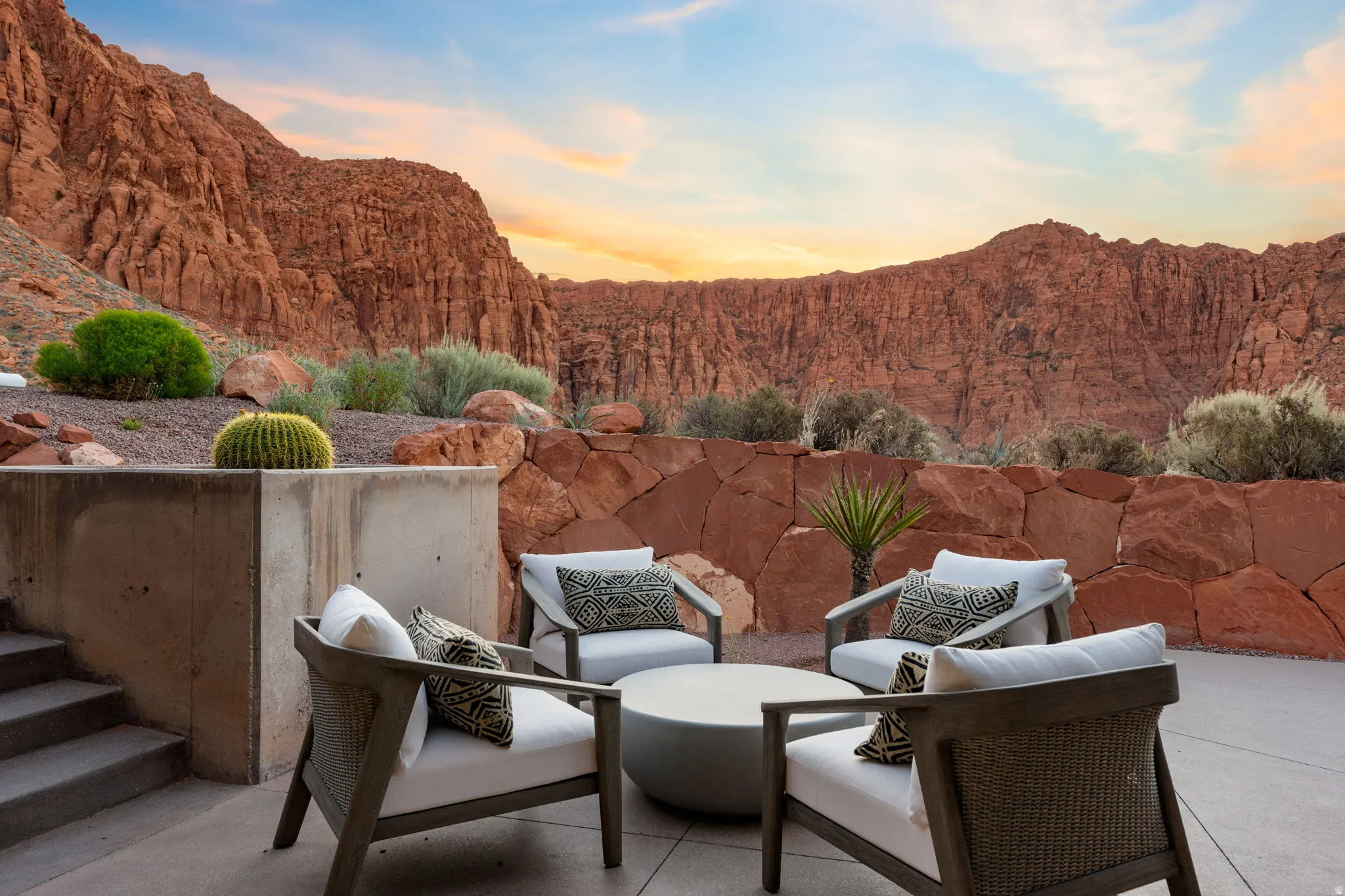 Expansive outdoor patio with concrete flooring, stone retention walls, and desert landscaping