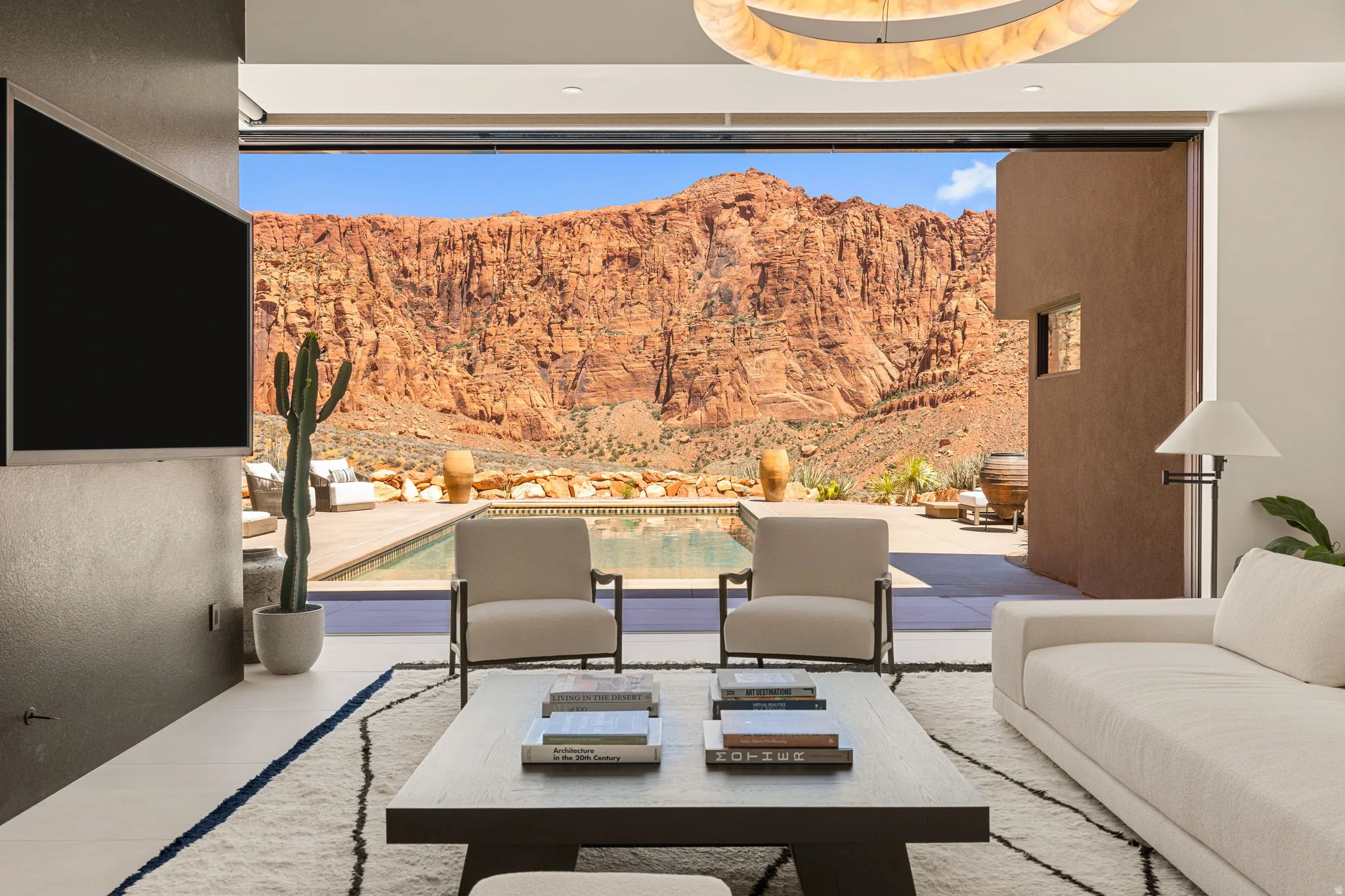 Spacious living area with sliding glass wall, white tile flooring, and a stone-clad accent wall