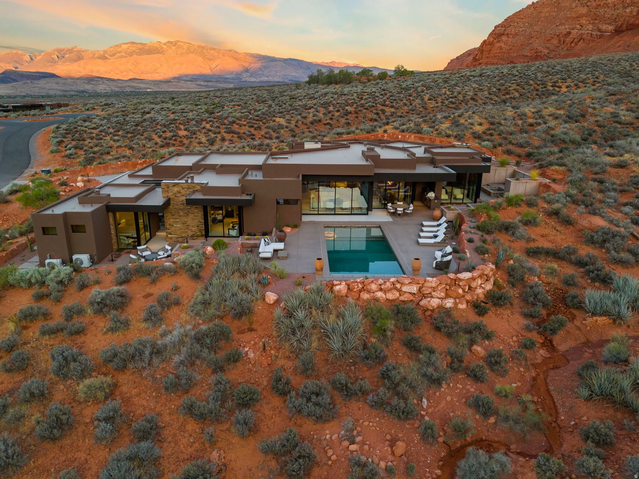 Modern exterior architecture with integrated outdoor living spaces, a rectangular swimming pool, and a stone retaining wall