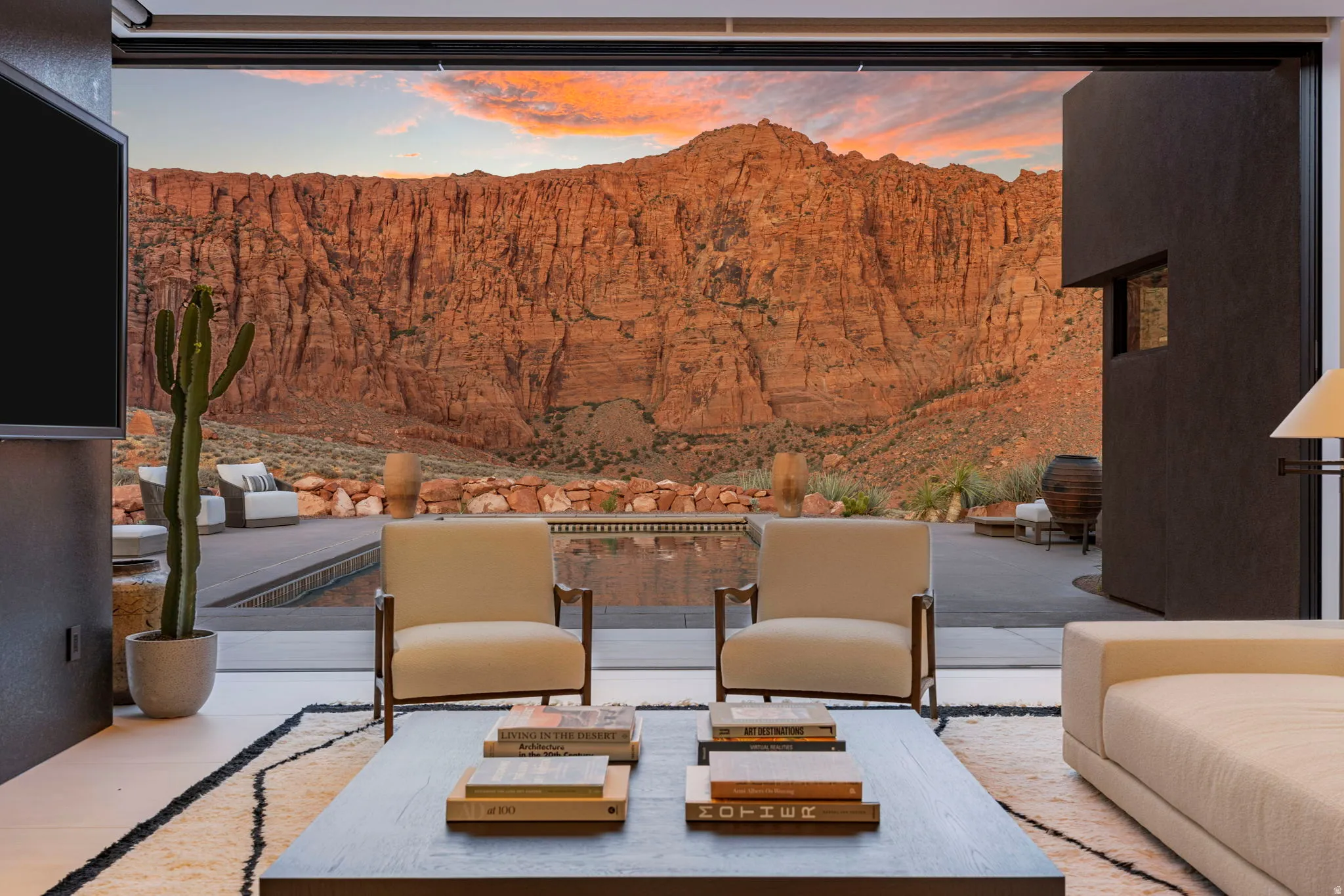 Expansive retractable glass wall, concrete patio with integrated pool, and a natural rock wall backdrop
