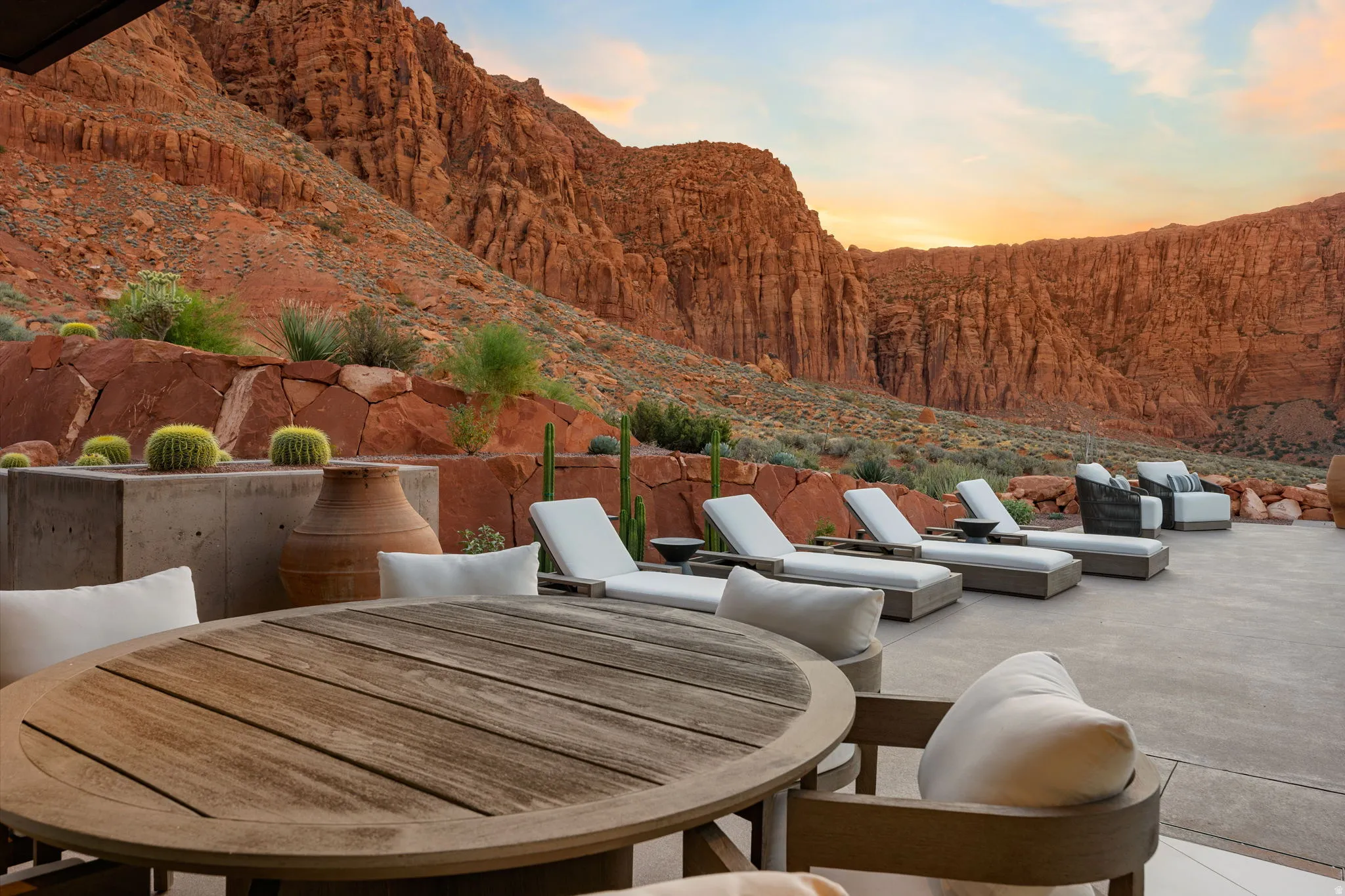 Expansive outdoor patio with concrete paving, a built-in planter with desert flora, and surrounding natural rock formations