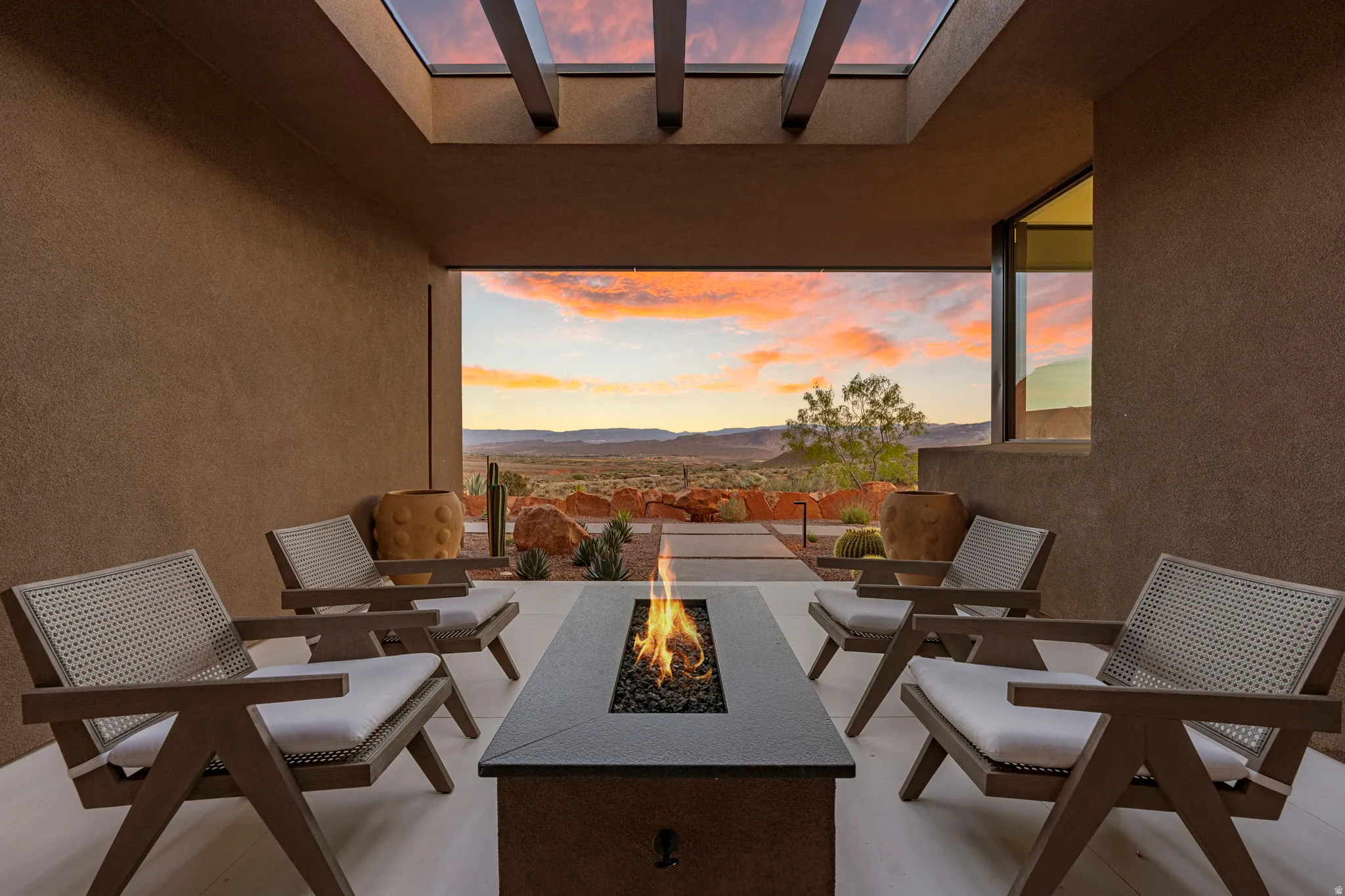 Covered patio with a built-in linear fire pit, overhead skylight, and expansive desert scenery