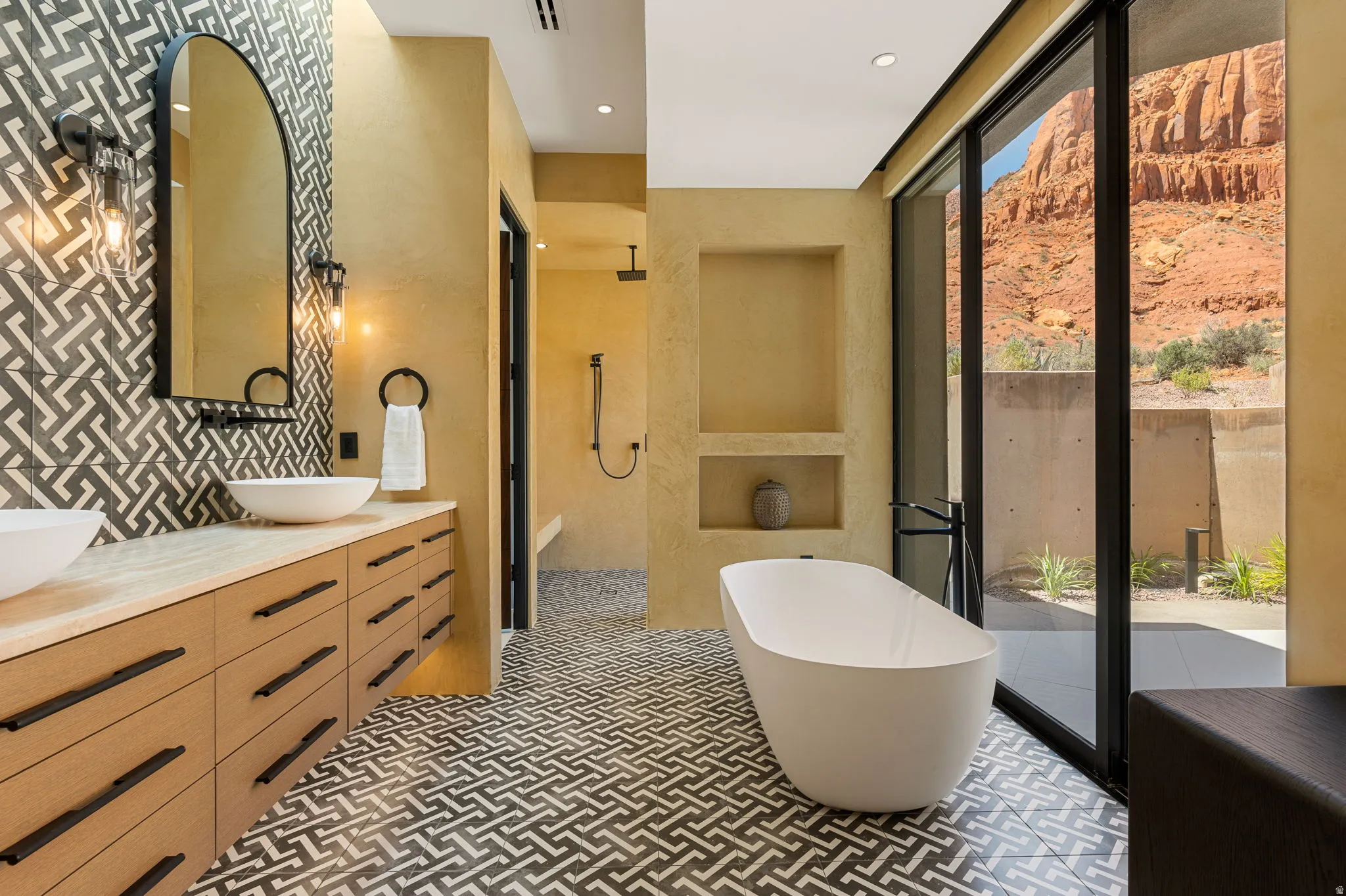 Dual vessel sinks on a wood-finish vanity with black hardware