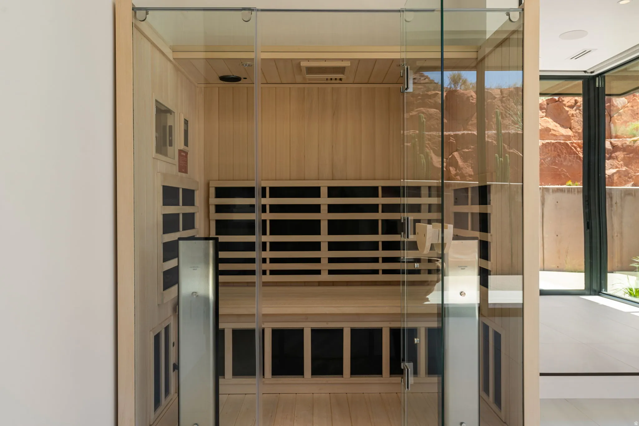 Built-in sauna with light wood paneling, glass door, and interior bench seating