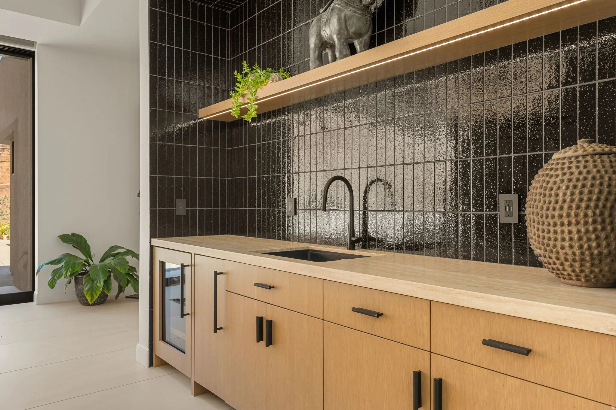 Wood-finish cabinetry with matte black hardware, integrated beverage cooler, and black sink with a contemporary matte black faucet