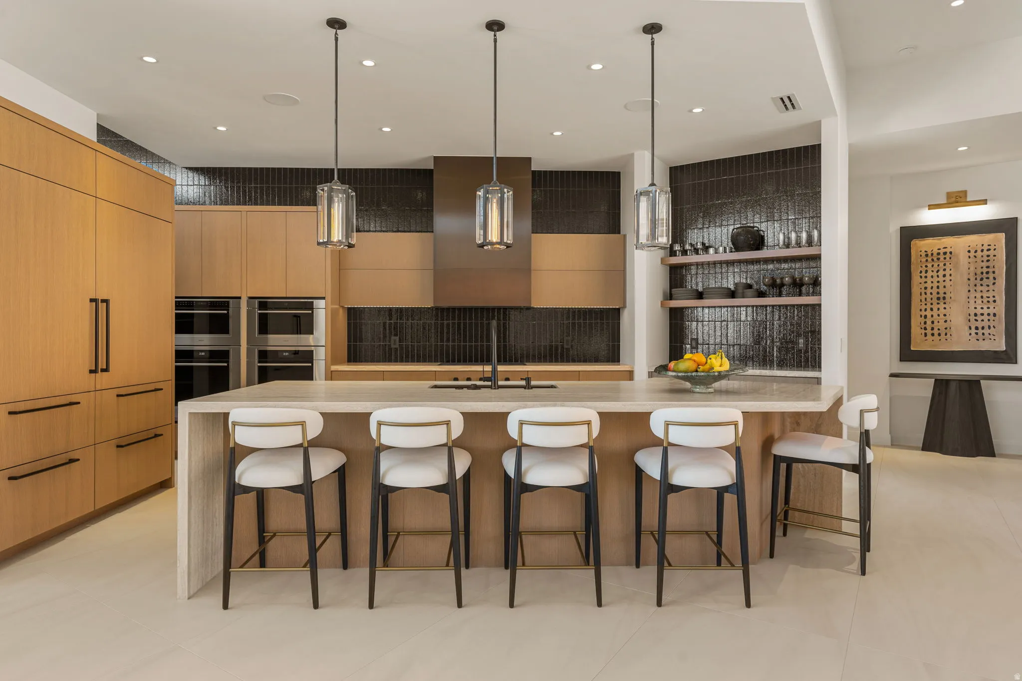Central kitchen island with a light-toned countertop, integrated dual ovens, a dark tile backsplash, wood-finish cabinetry, and recessed lighting