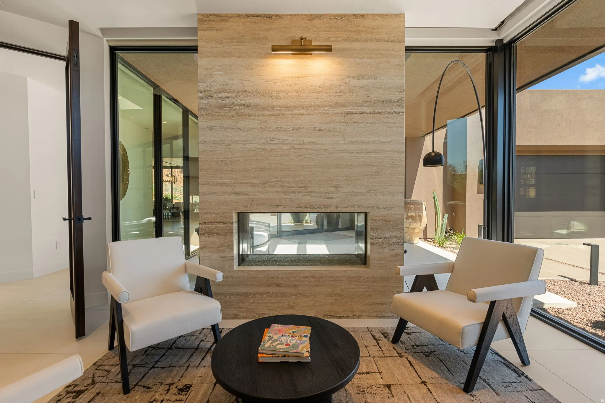 Full-height glass doors, stone-clad fireplace with a linear insert, and neutral-toned flooring