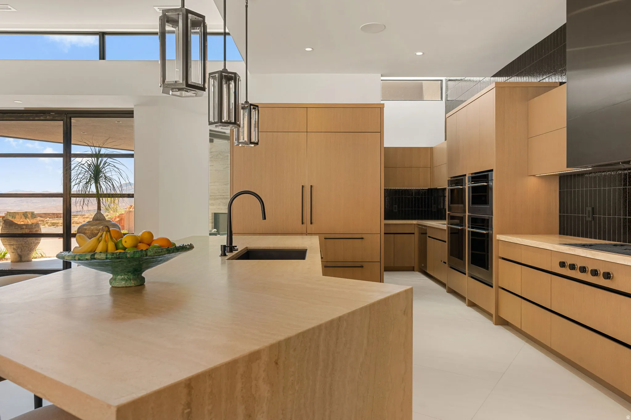 Kitchen featuring wood-finish cabinetry, integrated appliances, and a central island with an integrated sink