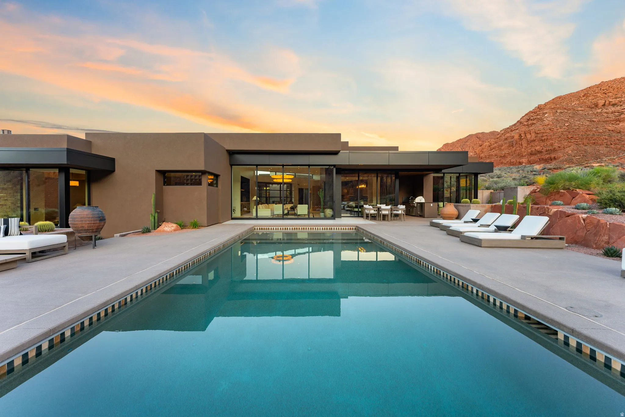 Modern exterior architecture with expansive glass sliders, outdoor dining area, a built-in swimming pool, and concrete patio