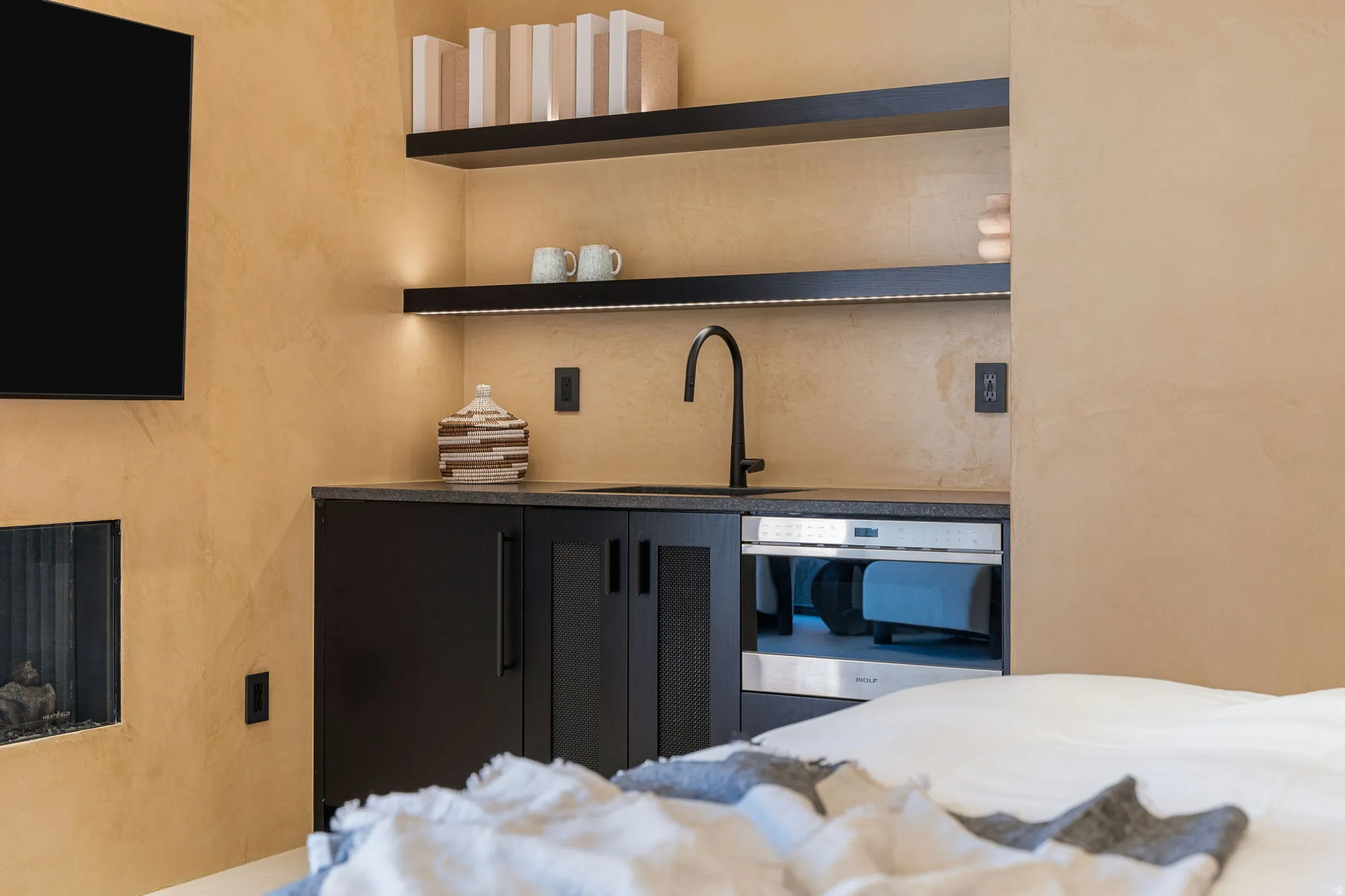 Built-in wet bar with dark cabinetry, integrated sink, and modern faucet