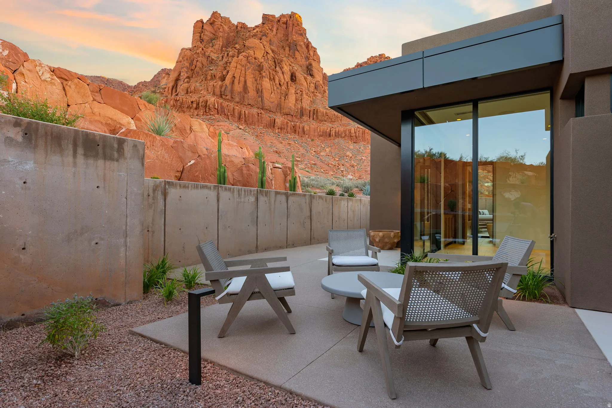 Private outdoor patio with concrete paving, natural stone aggregate landscaping, and full-height glass doors