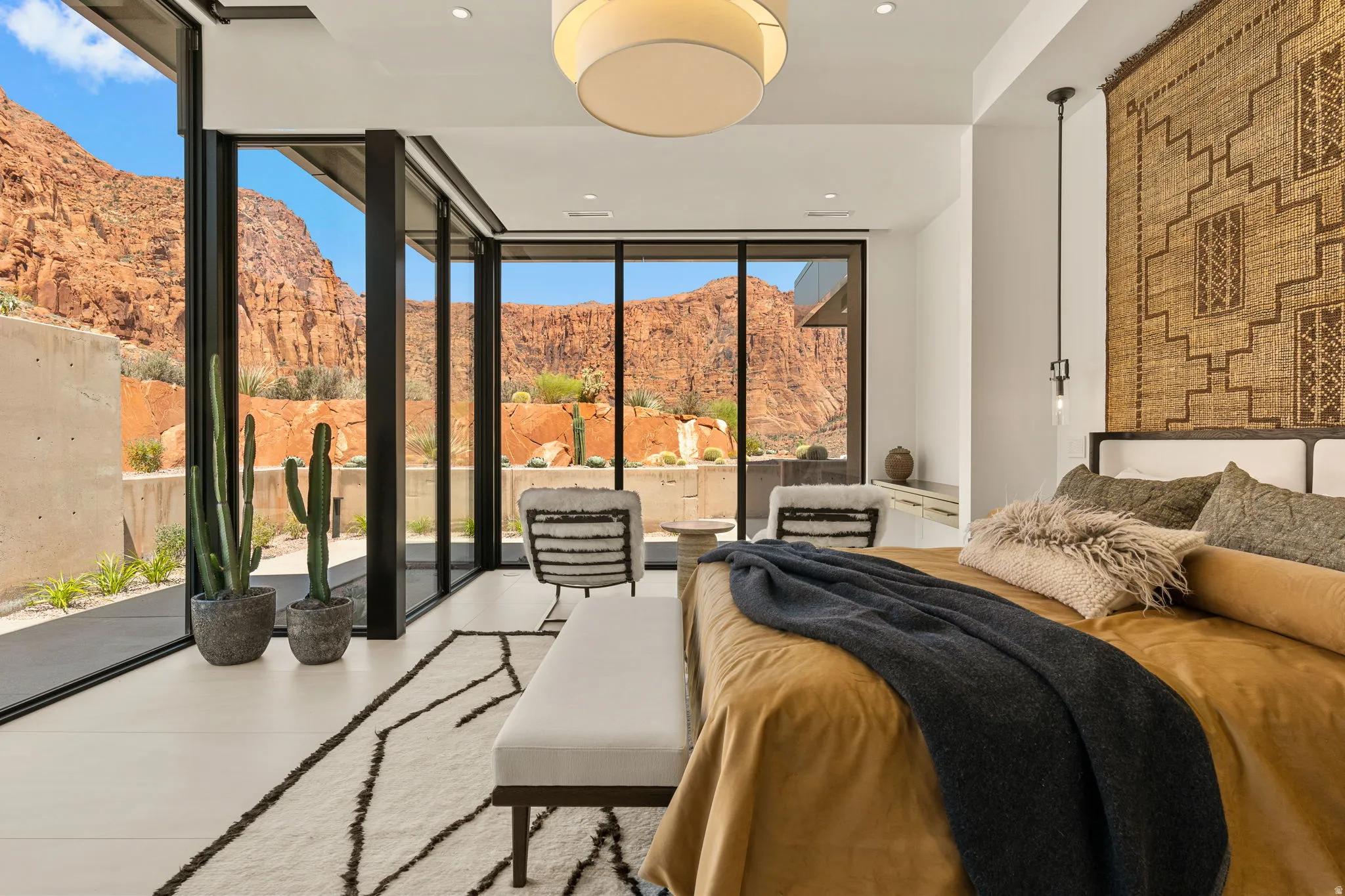 Expansive glass wall system, recessed lighting, ceiling-mounted light fixture, white flooring, and a large textile wall hanging
