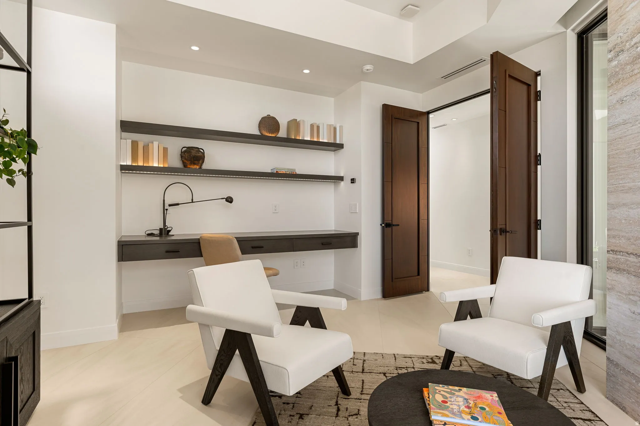 Recessed lighting illumination, wall-mounted desk with built-in drawers, floating shelving with integrated lighting, wood-finish flooring, and dark wood doors with dark hardware