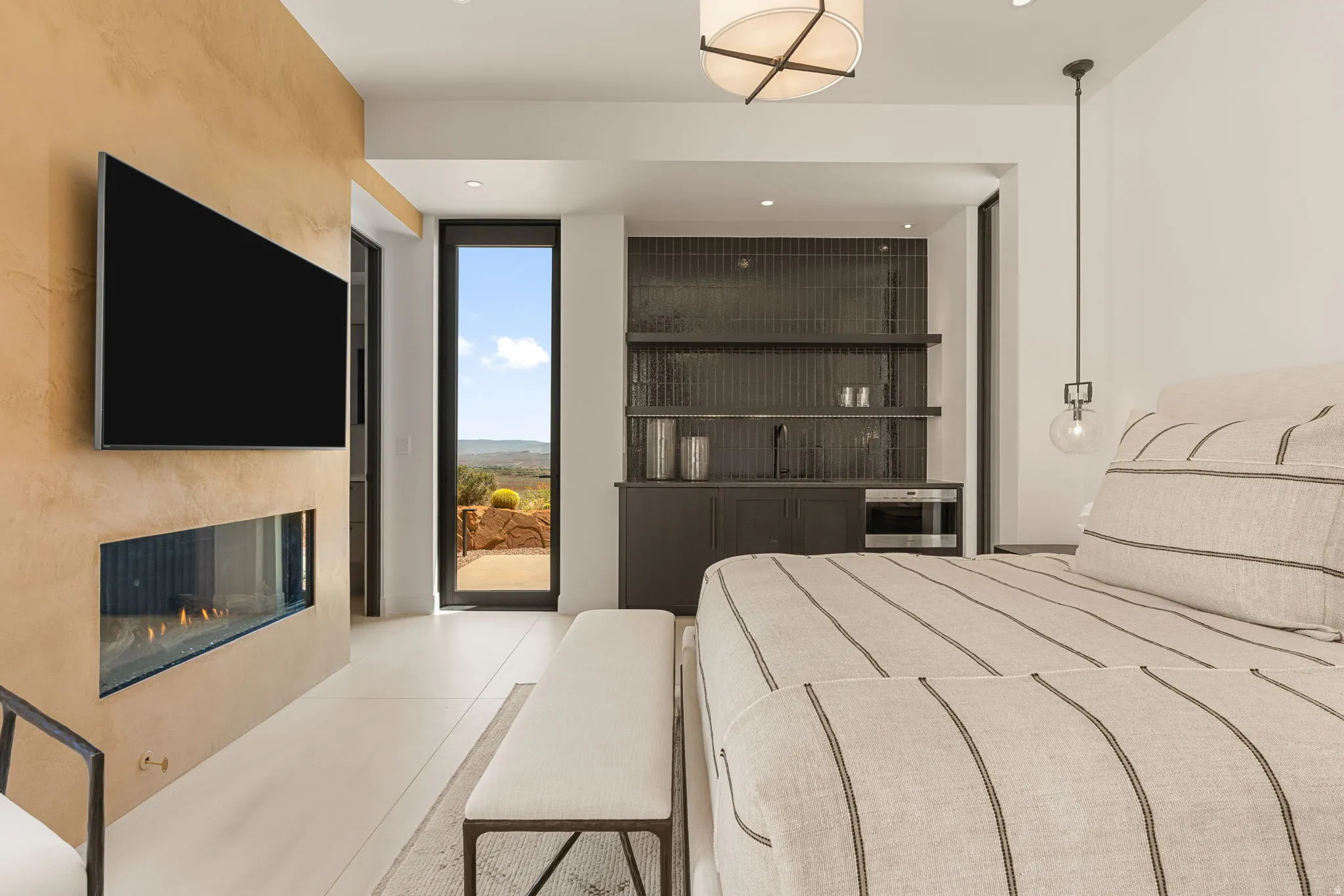 Built-in linear fireplace, wall-mounted television, integrated wet bar with open shelving, full-light exterior door, and recessed lighting