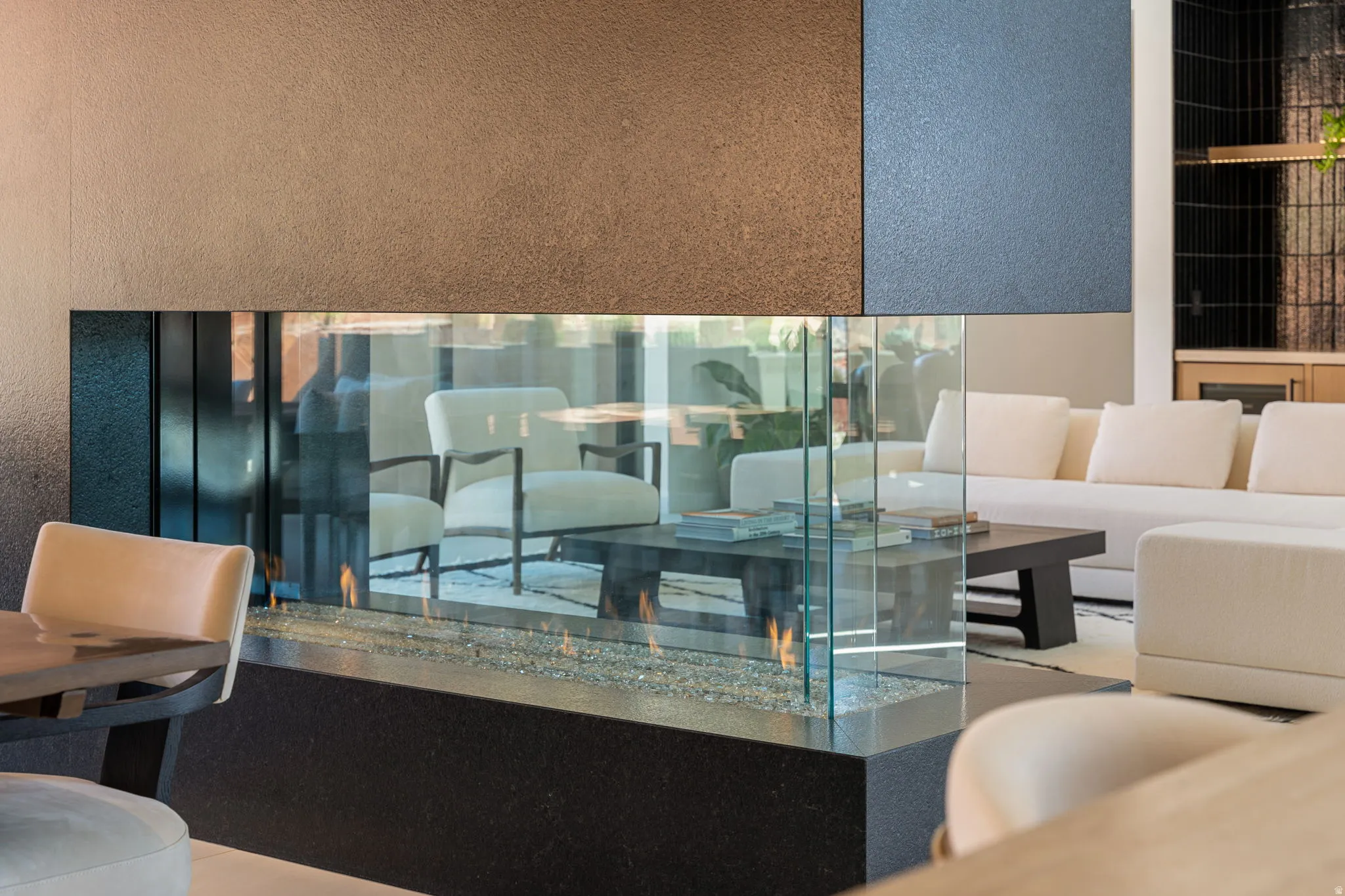 Double-sided glass fireplace featuring a dark stone base and pebble-fill fire bed