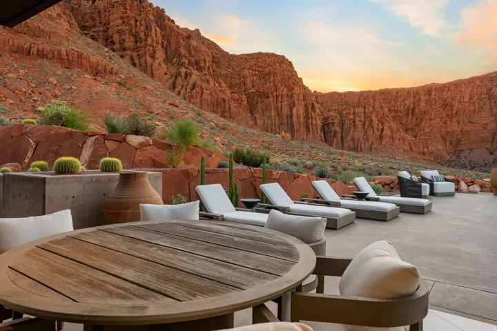 Expansive outdoor patio with concrete paving, a built-in planter with desert flora, and surrounding natural rock formations