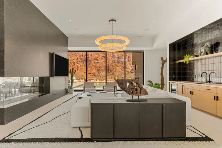 Full-height glass paneling, a linear gas fireplace, a built-in wet bar with wood-finish cabinetry, and a contemporary chandelier