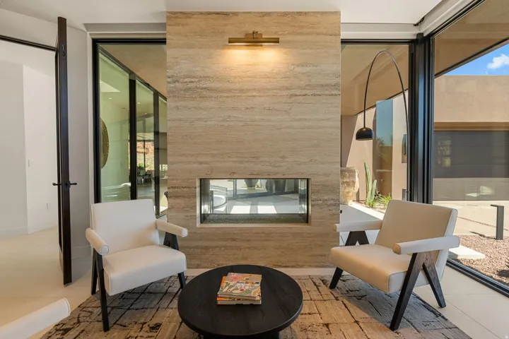 Full-height glass doors, stone-clad fireplace with a linear insert, and neutral-toned flooring